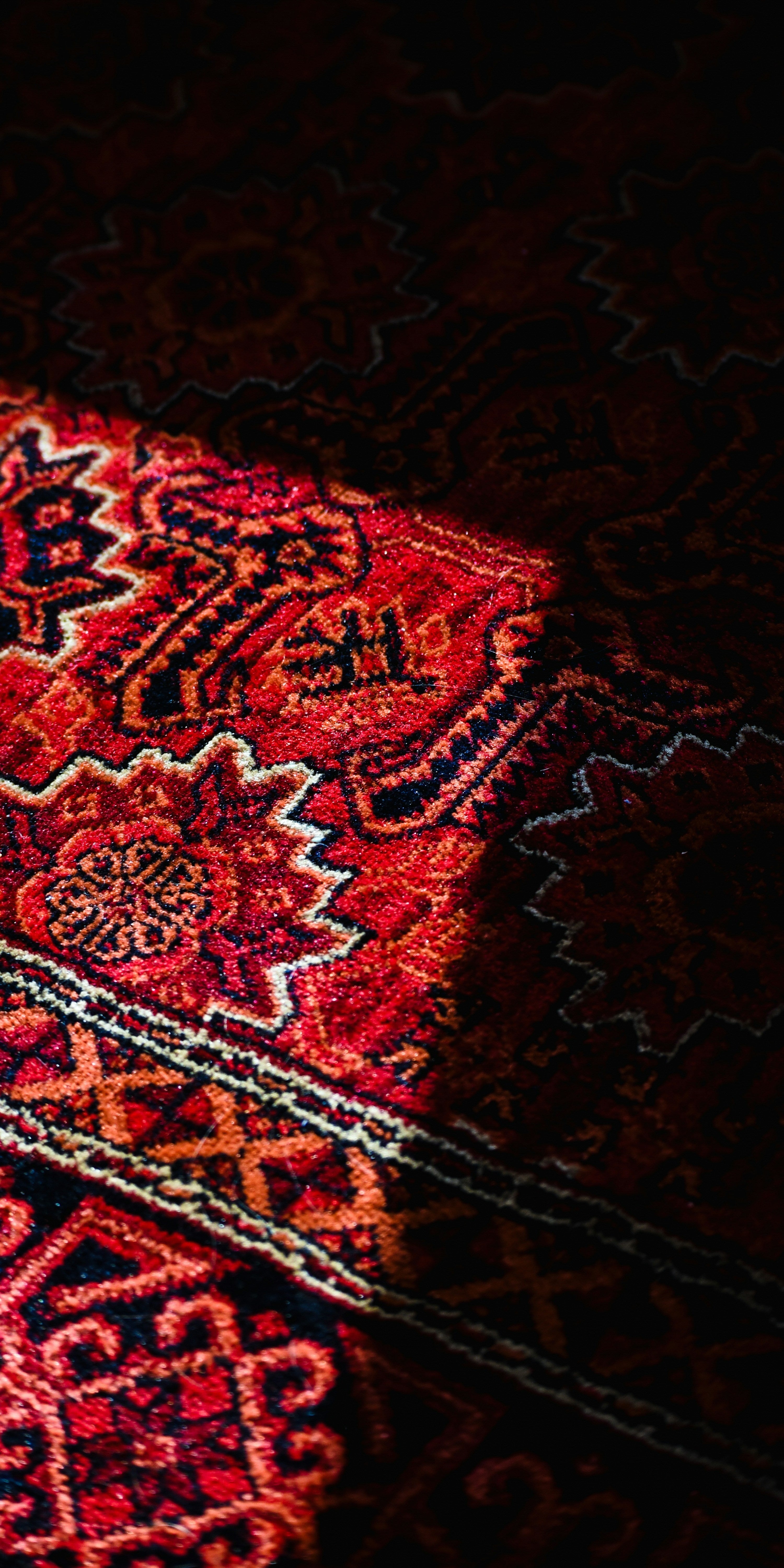 Gros plan sur un tapis persan aux motifs géométriques rouges et dorés
